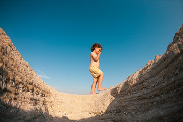 The boy walks along the sandy beach.