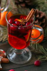 Mulled wine. Christmas hot drink with citrus, apple and spices in a glass cup on a wooden background.