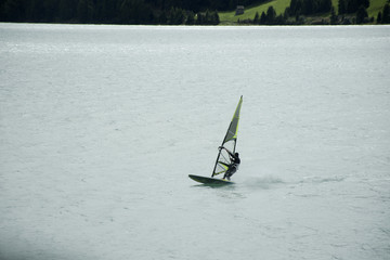 Sportsman people sailing windsurfing in Haidersee lakein Trentino-Alto valley at South Tyrol or Alto Adige in Bolzano or bozen city at Italy