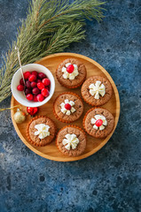Brownie mins pies on a wooden plate  on a blue stone background.