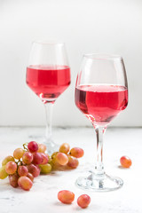 Pink wine and a grape on the white background
