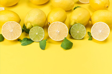 lemons and green limes with leaves on a yellow background