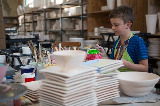 Boy Painting A Bowl In Pottery Shop
