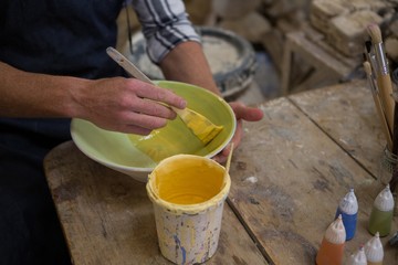 Male potters hand painting a bowl in pottery workshop