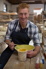 Male potter painting a bowl in pottery workshop