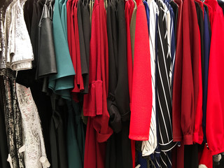 Modern clothes in a shop on a hanger. Shirts and sweaters of different colors and denim for youth.
