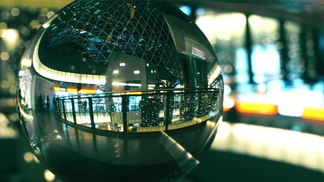 Unknown people walk in a modern shopping mall, view through the glass ball
