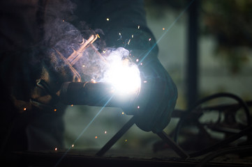 A man welds a metal with a welding machine