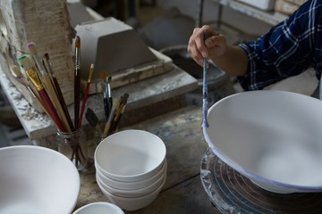 Female potter painting a bowl