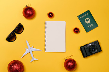 Christmas vacation concept - airplane, camera, notebook,  passport on yellow background