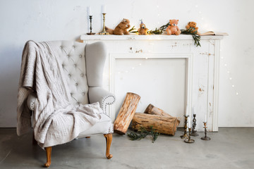 White minimalist loft interior with fireplace, armchair and christmas decorations.