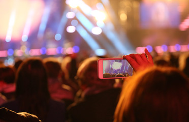 girl takes a photo with the smartphone during the concert