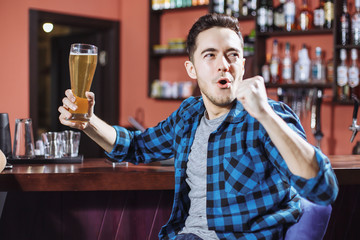 Emotional young man with a beer at a bar