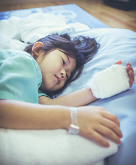 Illness asian child admitted in hospital with saline iv drip on hand.