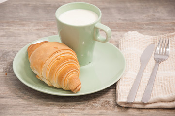 Freshly baked croissant and cup of milk