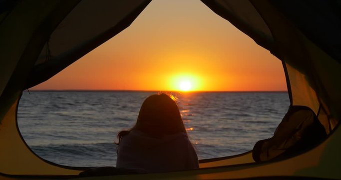 Close-up of a girl in a tent looking at sunrise