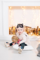 portrait beautiful little girl near the fireplace. Christmas tree decoration and light bulbs garlands