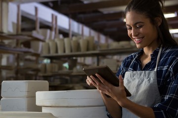 Fototapeta premium Happy female potter using digital tablet
