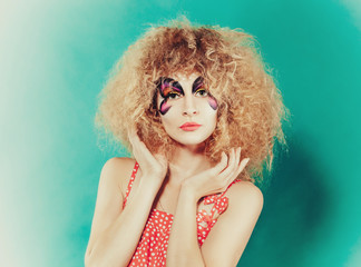 Naklejka premium Close-up portrait of beautiful sprite girl with butterfly faceart on tiffany blue background