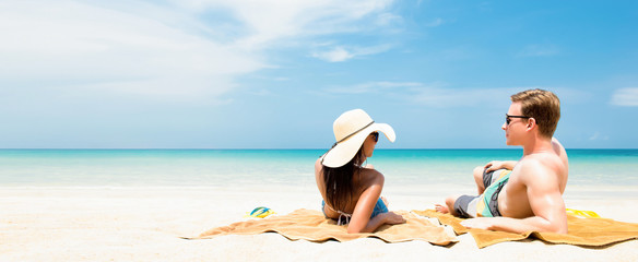 Couple lying on white sand beach relaxing and taking a sunbath in summer holidays