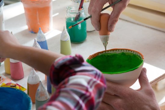 Male potter and girl painting bowl - Powered by Adobe