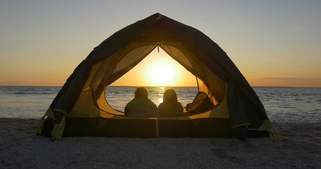 Romantic couple on the beach in the tent watching the sunrise - Powered by Adobe