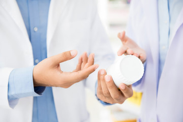 Pharmacists holding medicine bottle and discussing in pharmacy