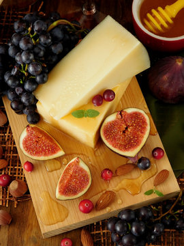 Parmesan on a board surrounded by figs and grapes. Ingredients for a cheese plate