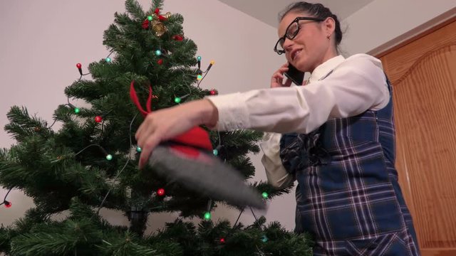 Woman with Christmas sock talking on phone near Christmas tree