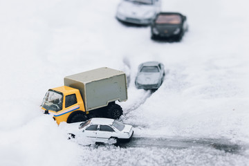 Symbolic car accident in winter on snow road staged with toy cars