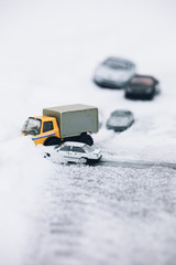Symbolic car accident in winter on snow road staged with toy cars