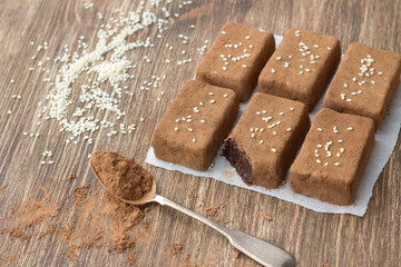 Chocolate sweets with dried fruits and sesame seeds on a wooden table, rustic style. Healthy homemade food