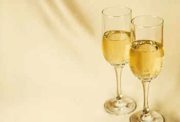 Foto op Aluminium two glasses of champagne on a background of a fabric of golden color © Oleg