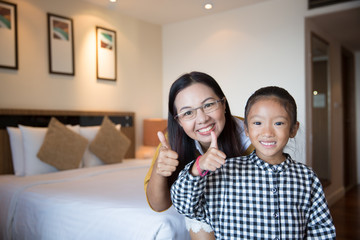 Mother and daughter enjoy relaxing in the hotel bed room on holiday