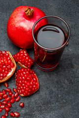 Pomegranate juice and seeds close-up on dark concrete background