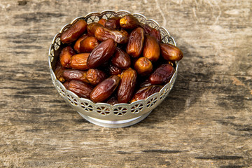 Dates fruit on a silver bowl on wooden table. The Muslim feast of the holy month of Ramadan Kareem