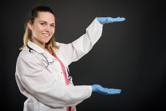 Young female doctor  holding copyspace and smiling