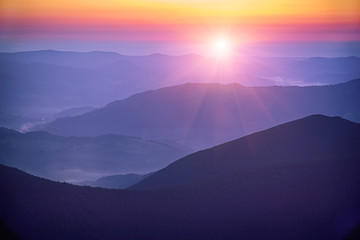 Amazing mountain landscape with colorful vivid sunrise on the bright sky over blue hills, natural...