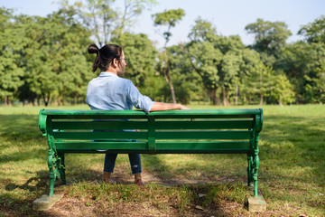 Asian woman sitting on bench in the gargen.