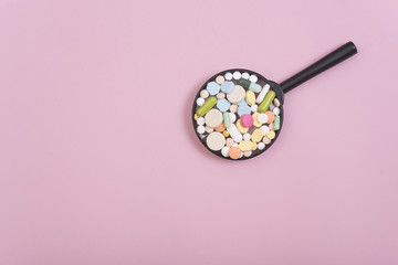 colorful medicine on magnifying glass pharmacy on pink background.