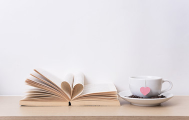 tea cup with red heart on book shelf. Valentines day vintage background.