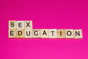 Wooden blocks on a pink background spelling words Sex Education