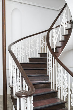 Spiral stair case in colonial style with steps and hand rails made from dark wood