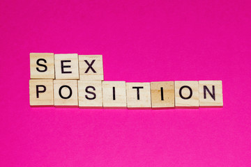 Wooden blocks on a pink background spelling words Sex Position