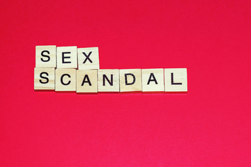 Wooden blocks on a red background spelling words Sex Scandal
