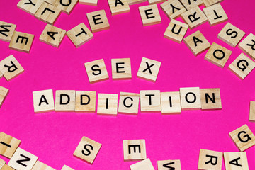 Wooden blocks on a pink background spelling words Sex Addiction