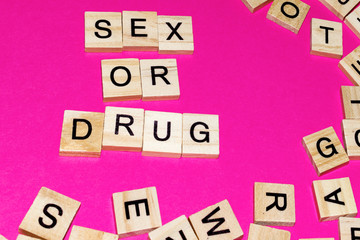 Wooden blocks on a pink background spelling words Sex or Drug