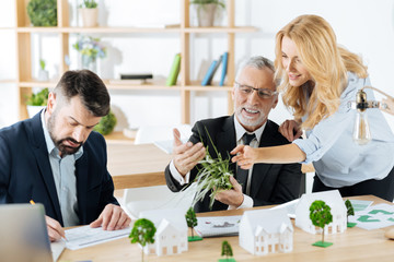 Amazing. Positive emotional smart colleagues of the progressive real estate agency thinking of adding flowerbeds with synthetic grass to one of the houses while sitting together