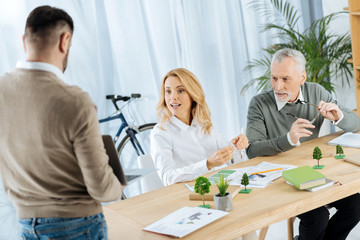 Presentation. Excited emotional engineers feeling surprised while sitting in the office and looking at the screen of a modern tablet when listening to the presentation of their colleague