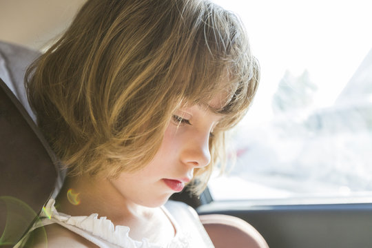 Cute Small Child, Blonde Girl, In Car Seat Wearing Seat Belts Happy Is Going To Go In The Path Of The Road, Sun Glare Reflected